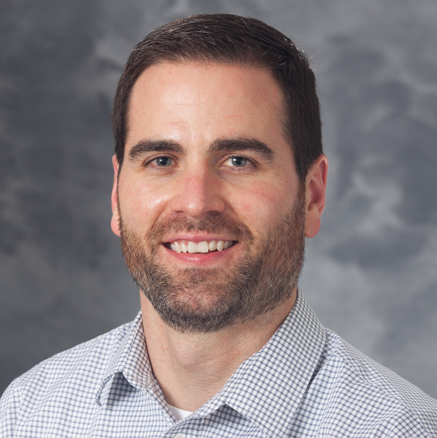 Mike, who is White with short brown hair, smiling in front of a grey background.